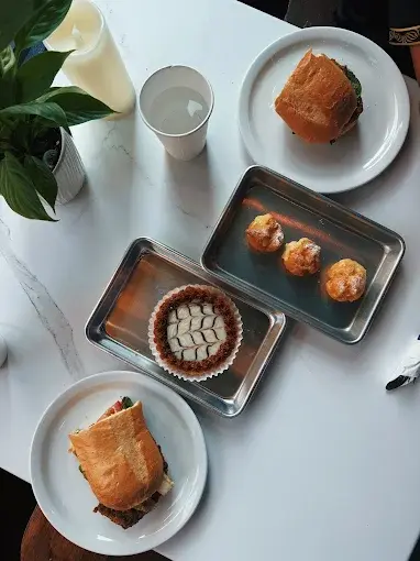 A table spread of sandwiches, profiteroles and a tart